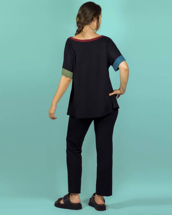 Blusa negra de manga corta con aplicaciones de colores con pantalones negros de punto.